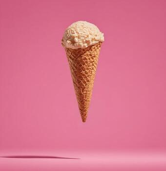Close-up of a waffle cone with a single scoop of ice cream floating over pink background photo