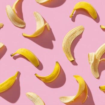 Overhead view showing several yellow bananas and peels scattered against a pink background photo