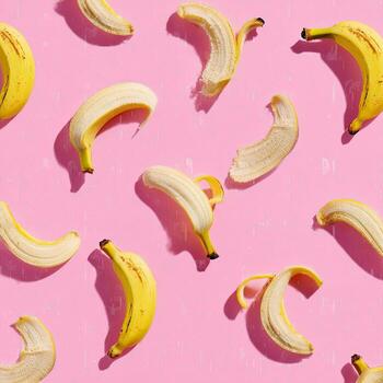 Yellow bananas, some peeled, scattered over a pink textured background, creating a vibrant pattern photo