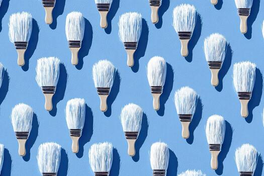Pattern of paint brushes with white bristles and wooden handles, arranged on a blue backdrop photo