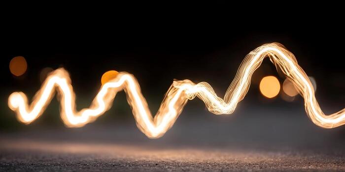 A bright glowing light trail creates an abstract wavy pattern in a dark environment with blurred background lights photo