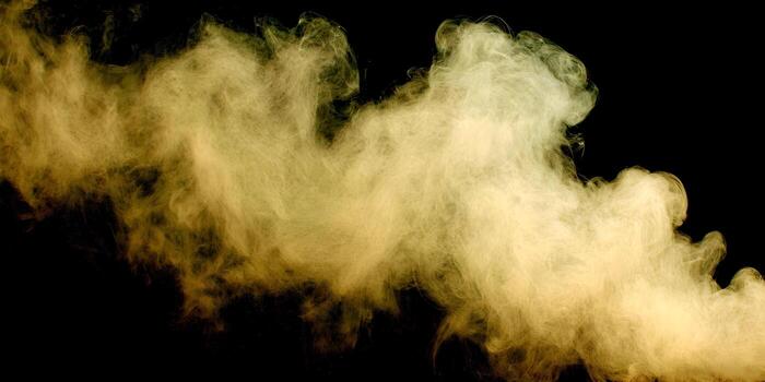 A dynamic golden yellow smoke cloud billows and swirls dramatically against a dark black background photo
