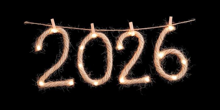 The year 2026 is crafted from illuminated natural rope with festive lights and hangs on a string against a black background photo