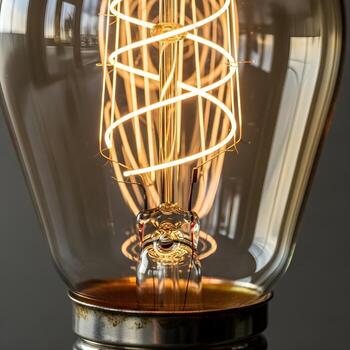 Gleaming Vintage Icon Macro Capture of an Antique Lightbulb with Gently Glowing Filaments, Sleek Metallic Textures and Subtle Ambient Reflections for Upscale Minimalism photo