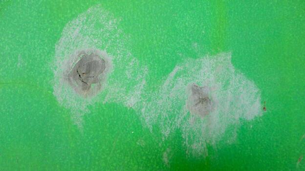 Abstract texture of a worn and scratched green surface with two circular impact marks photo