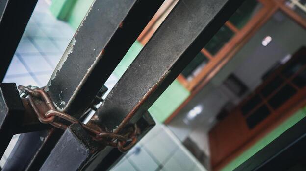 Weathered metal gate secured with a sturdy, rusty chain, offering a visual representation of robust security and property protection photo