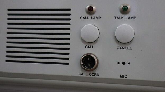 Close-up of an intercom panel with buttons, lamps, and cord connection port photo