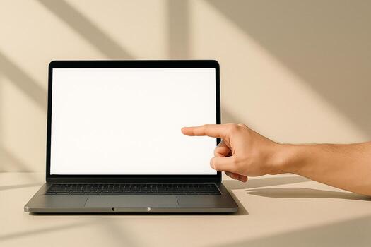 Hand pointing to a blank laptop screen on a table with soft shadows cast from a window photo