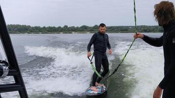 man surfing på en wakeboard medan varelse bogserad förbi en båt i en dynamisk vatten scen video