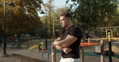 en omtänksam man vilar i en parkera under höst med en lekplats synlig Bakom video