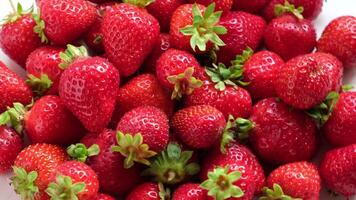 Strawberry on a white background. Strawberry background. Red fresh strawberry wallpaper. Macro. Texture. Frame with copy space. Lots of freshly picked Berries rotating on turntable. Close up. 4K. video