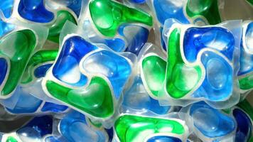 bakgrund av olika färgrik kapslar med tvätt rengöringsmedel och diskmaskin tvål. lugg av flera olika tvättning pod kapslar är roterande. rengöringsmedel tabletter. topp se, platt lägga. se från ovan. stänga upp. video