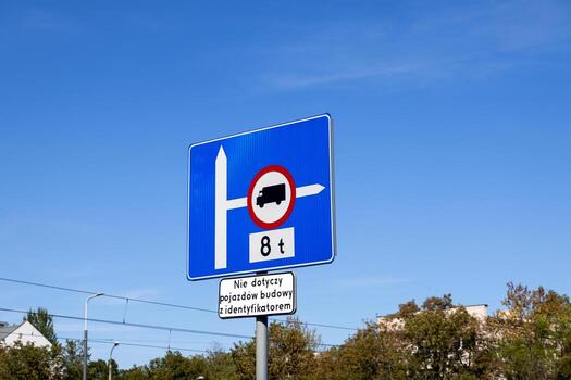 Blue road sign displaying a heavy vehicle weight restriction of 8 t with white directional arrows, clarifying traffic rules for urban planning and transportation photo
