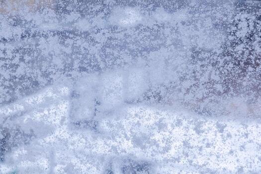 Frosted window pane displaying delicate ice crystals, creating a beautiful frozen texture ideal for a cold winter season background or decorative overlay photo