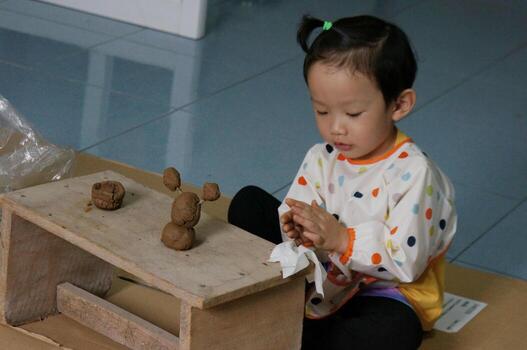 Adorable child focused on playing with clay, engaged in the process of creation. The child is seated at a wooden table, molding the clay with focus and care photo