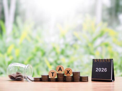 2026 desk calendar, Wooden blocks with the word TAX and stack of coins. Concept about saving money and manage time to paying tax in year 2026 photo