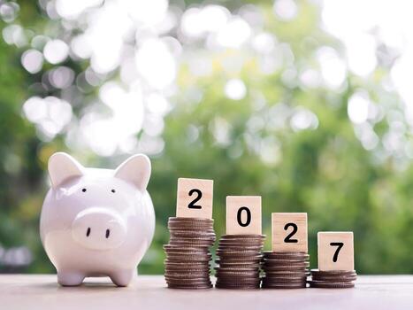 Piggy bank, Wooden blocks with the number 2027 on stack of coins. The concept of saving money, Financial, Investment and Business growing in year 2027. photo