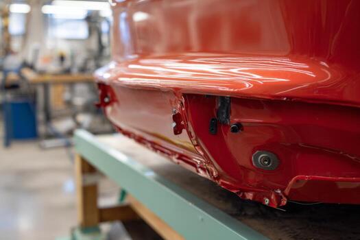 A red car is being worked on in a factory photo