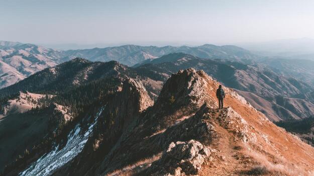 man standing on top of mountain in mountains photo