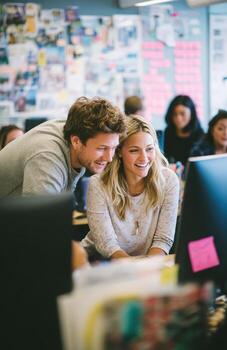 Smiling colleagues working together on computer in busy office photo