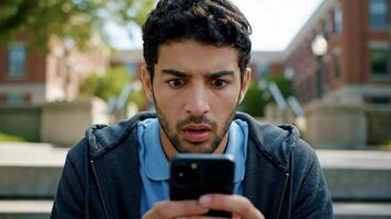 Man Looks Shocked While Using Phone on University Campus During Daytime video