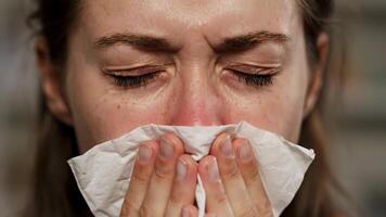 Frau mit ein kalt weht ihr Nase mit ein Gewebe beim Zuhause während das Tag video