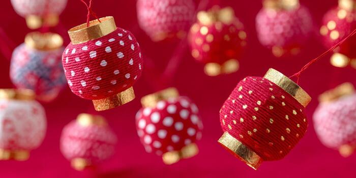 Multiple small lanterns with red and white polka dot patterns hang against a vibrant red background. The lanterns feature gold accents and are suspended by thin red strings. photo