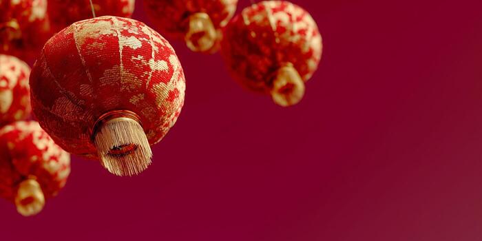 Several red Chinese lanterns with gold patterns hang against a plain red background. The image features a close-up view, emphasizing the festive decorations. photo