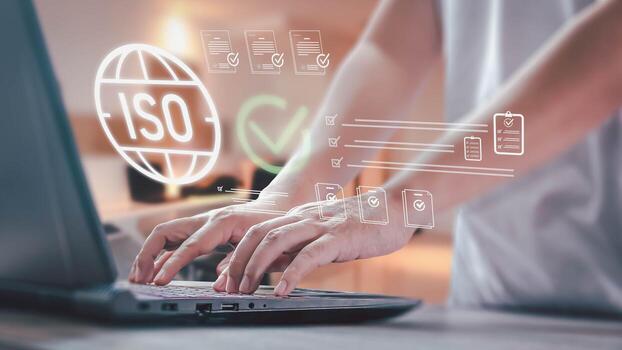 A person works on a laptop with a digital interface showing icons for international standards, checklists, and documents, representing quality control and certification processes. photo