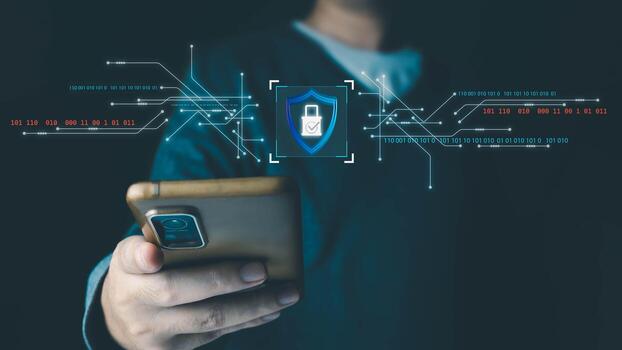 A person holds a mobile phone with a holographic display showing a security shield icon, representing data protection and online cybersecurity on a dark background. photo