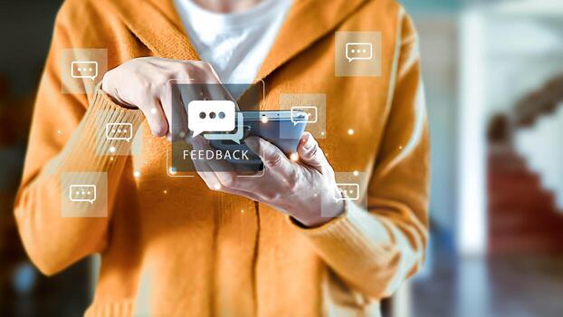 A person in a yellow sweater holds a mobile phone, touching the screen to send feedback. Digital message icons are overlaid, representing customer experience and online communication. photo