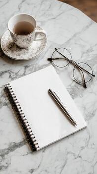 Cozy Workspace With Notebook, Pen, and Tea on a Marble Table During a Quiet Afternoon photo