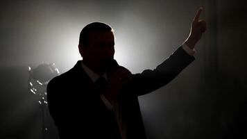 Silhouette of a Man Giving a Speech with a Microphone in a Dark Setting video