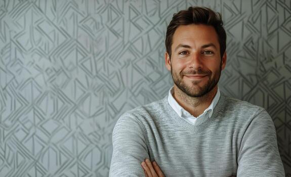 Smiling Man in Gray Sweater Against Patterned Background in Modern Indoor Setting photo