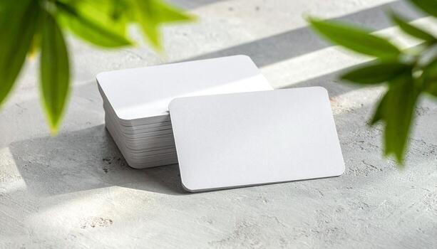 Blank White Business Cards Stacked on Textured Surface with Natural Light and Green Leaves Shadows Minimalist Design Mockup Template photo