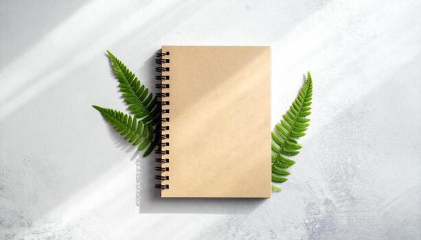 Minimalist Kraft Notebook with Delicate Ferns and Sunlight Shadows on a Textured White Background Top View Copy Space photo