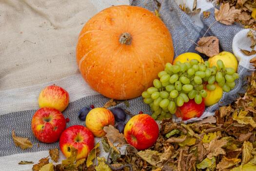 An inviting fall tableau with a central pumpkin, complemented by an array of fruits and a vibrant flower arrangement photo