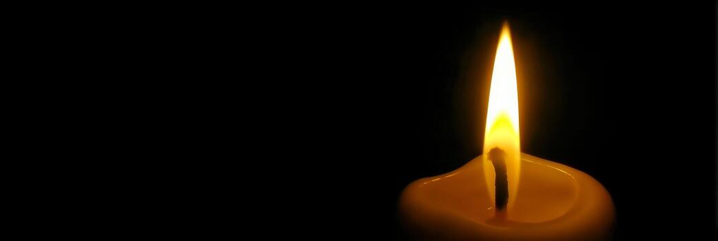 Lonely candle flickers softly in dark setting, symbolizing memory and reflection photo