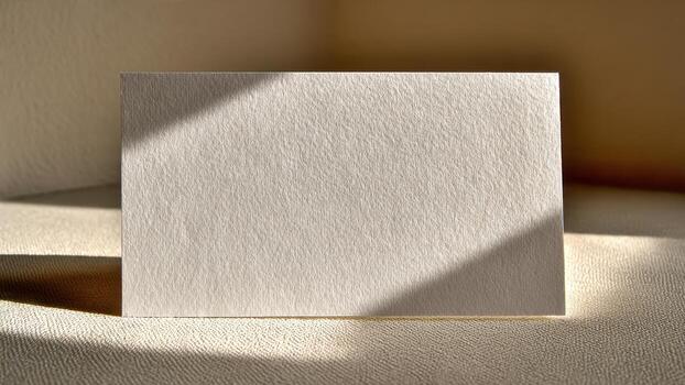 Blank textured paper card casting shadow on beige surface soft light empty photo