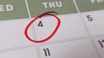 de 4:e av de kalender är ringade in i röd markör i en närbild makro skott på en vit sida, symboliserar ett Viktig dag eller påminnelse. video