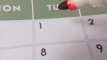 il 1 ° Data su un' calendario è cerchiato con un' rosso marcatore nel un' avvicinamento macro tiro su un' bianca pagina, simboleggiante un importante giorno o promemoria. video
