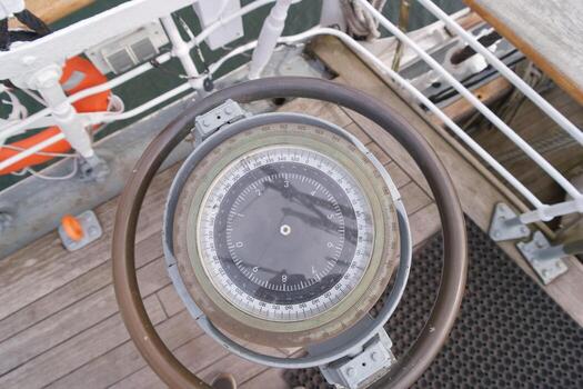 Navigational compass on a classic sailing vessel in calm waters during daytime photo