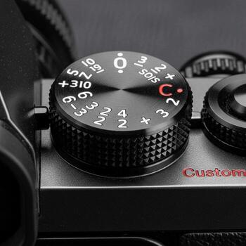 Close up of a black camera dial with aperture settings and a red c indicating a custom mode setting photo