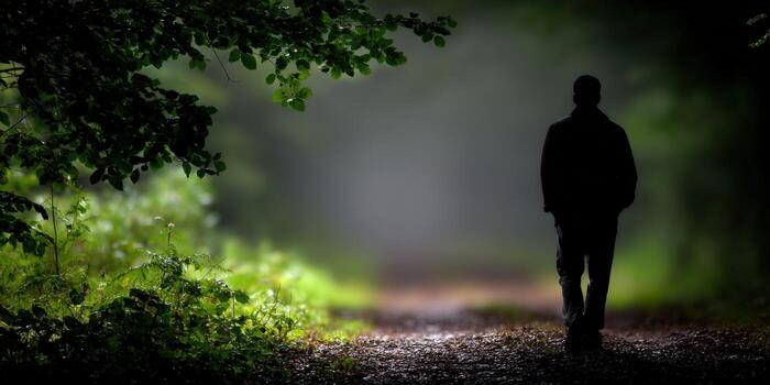 A man is walking down a path in the woods photo