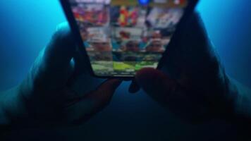 proche en haut de les doigts émouvant et défilement sur mobile application. sur une bleu néon tons Contexte. l'Internet navigation, social médias commercialisation. flou macro. Haut vue foncé coup video