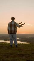 Silhouette of child throwing plane soaring into sky in front of him into brightly lit sunset horizon. After throw, dreamy boy runs towards us after airplane with arms open to sides as if he were flying. video