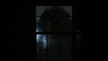 Visualizza di il finestra con montanti e bagnato bicchiere con gocce di pioggia. lampeggiante alleggerimento di temporale riflettendo nel il bicchiere. vicino su tiro a partire dal dentro il edificio video