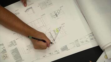 arkitektur design projekt, arkitekt designer teknik team diskutera interiör och skrivning anteckningar på de teckning av byggnad, golv planen, utarbetande tryckt på papper. video