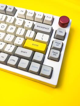 Closeup vertical keyboard with bright Enter key on bright yellow background, minimalism, keyboard buttons. A keyboard with a yellow key on the bottom left photo