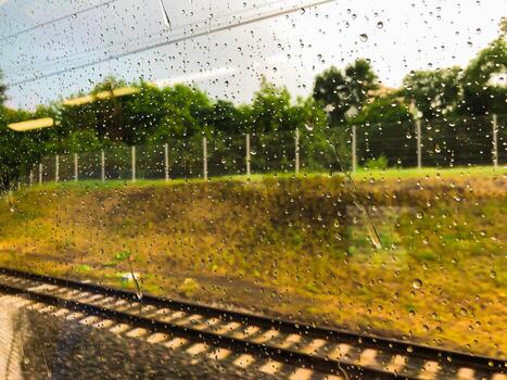 View of the railway from a train carriage, drops of water on the train window, train travel photo
